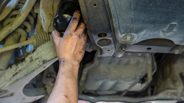 Technician change car oil filter under car. Mechanic doing car service and maintenance. Oil and fuel filter changing. Car maintenance concept. Mechanic changing the oil filter at an auto shop
