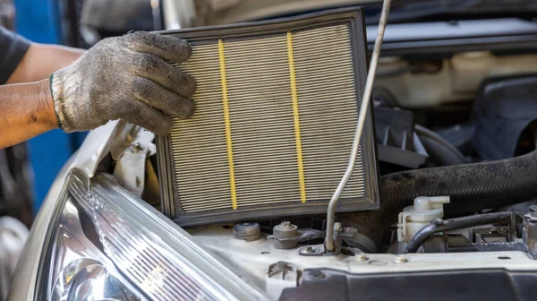 Mechanic is checking and change an air filter. Car mechanic working maintenance checking air filter in repair garage.