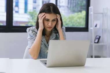 Modern ofis bilgisayarında çalışan bir iş kadını. Dizüstü bilgisayarda çalışan ciddi bir kadın. Ciddi yetişkin bir kadın dizüstü bilgisayarını izliyor ve evde çalışıyor..