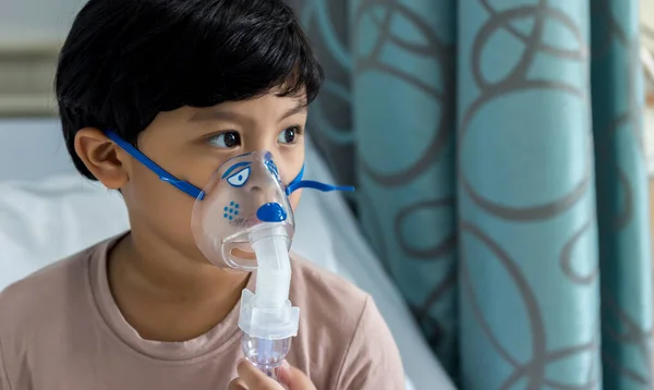 Sick boy inhalation therapy by the mask of inhaler. Baby has asthma and need nebulizations. Patient Boy use inhalation with Nebulizer mask at hospital. The baby are spraying bronchodilators .