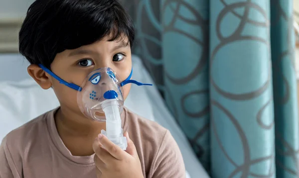 Sick boy inhalation therapy by the mask of inhaler. Baby has asthma and need nebulizations. Patient Boy use inhalation with Nebulizer mask at hospital. The baby are spraying bronchodilators .