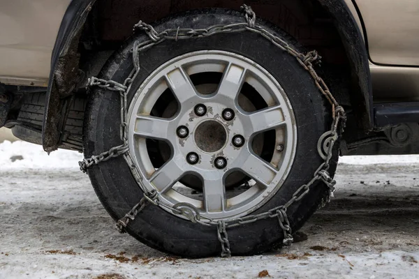 Wheel Car with winter chains for snow and ice road . Snow chains on tire. The wheel of a car with snow chain