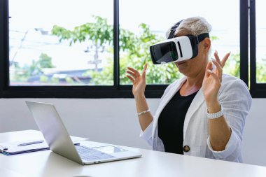 Video kaydedici kulaklıklı iş kadını. Online oyun için VR gözlük kullanan bir kadın. İş kadını güvenlik arayüzü ile ofis binasında oturuyor ve sanal gerçeklik kulaklığı kullanıyor.