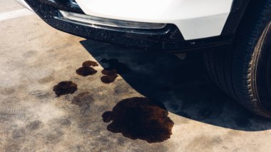 Beton zeminde motor yağı sızıntısı var. Beton zeminde siyah motor yağı. Motordan motor yağı sızıyor. Motor yağı lekeli yüzey betonu gri siyah gümüş..