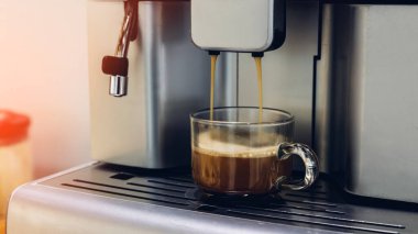 Kendi kendine hizmet eden kahve makineleri otelde, spor kulübünde ya da ofiste sürekli kaliteli kahve sunuyor. Espresso cappuccino kahve makinesi masanın üstünde. Espresso makinesinden kahve dökülüyor. Barista. 
