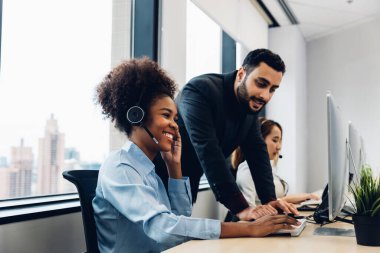 Call center business woman talking on headset. Call center worker accompanied by her team. Customer service executive working at office.	