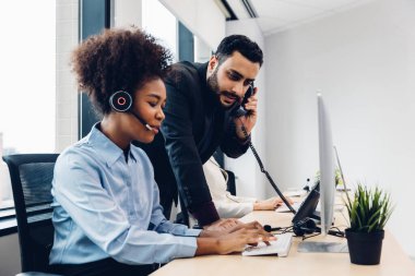 Call center business woman talking on headset. Call center worker accompanied by her team. Customer service executive working at office.	