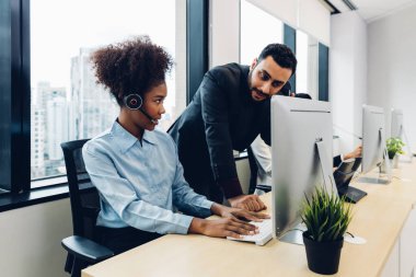 Call center business woman talking on headset. Call center worker accompanied by her team. Customer service executive working at office.	