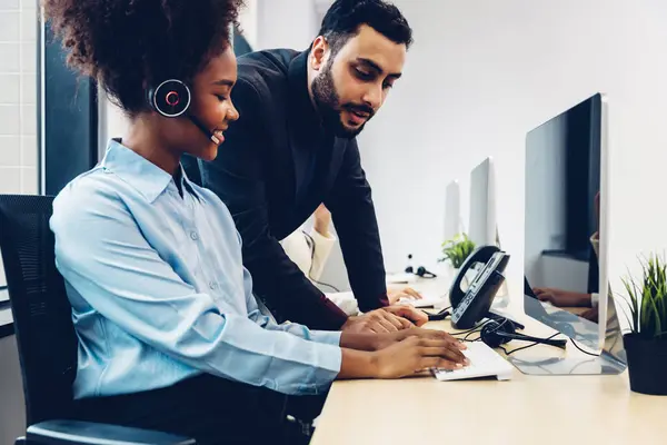 stock image Call center business woman talking on headset. Call center worker accompanied by her team. Customer service executive working at office.	