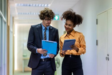 Çeşitli arkadaş ortaklar modern ofis koridorlarında yürümekten bahseder. Ofiste yürüyen ve konuşan kendine güvenen iş ortakları. Profesyonel iş adamları yürüyor ve konuşuyor.