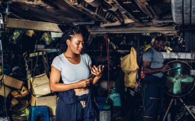 Professional Car Mechanic is Investigating Under a Vehicle on a Lift in Service. Auto Service Worker Checking Car Under Carriage Look For Issues. Car service technician check and repair customer car.