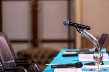 Konser salonunda mikrofon ya da konferans odasında arka plan için yumuşak ve bulanık bir tarz. Konferans salonu veya seminer salonu arkaplanının bulanık fotoğrafı üzerine mikrofon.