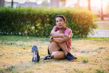 Protez bacaklı bir sporcu parkta egzersiz yapıyor. Koşu için protez ekipman takan bir kadın. Protez bacaklı bir kadın.