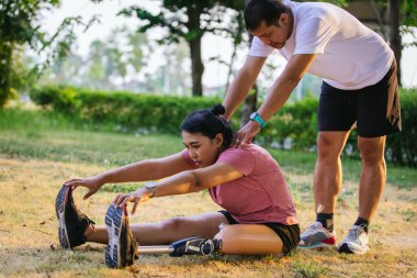 Protez bacaklı bir sporcu parkta egzersiz yapıyor. Koşu için protez takan kadın..