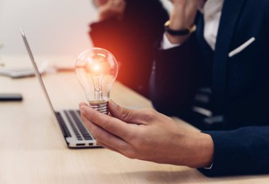 Elinde ampul tutan bir iş adamı. Yenilikçi ve ilham verici bir fikir. İş adamı elinde ampul tutuyor. Beyin yaratıcı düşünceler ve yenilik kavramı.