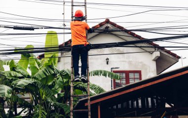 Ahşap merdivendeki teknisyen Fiber Optik Kabloları kontrol ediyor. Merdivendeki teknisyen dijital kablo sistemini kontrol et ve kaldır
