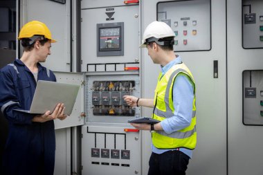 Electrical engineer working in control room. Electrical engineer man checking Power Distribution Cabinet in the control room clipart