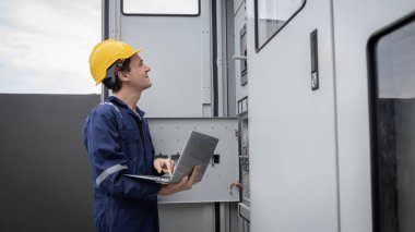 Kontrol odasında çalışan elektrik mühendisi. Elektrik mühendisi kontrol odasındaki güç dağıtım dolabını kontrol ediyor.