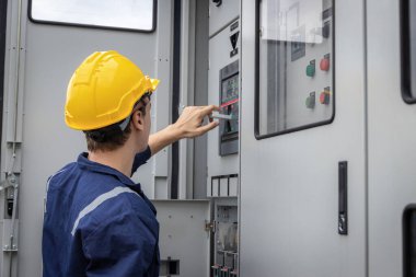 Kontrol odasında çalışan elektrik mühendisi. Elektrik mühendisi kontrol odasındaki güç dağıtım dolabını kontrol ediyor.