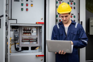 Kontrol odasında çalışan elektrik mühendisi. Elektrik mühendisi kontrol odasındaki güç dağıtım dolabını kontrol ediyor.