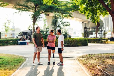Arkadaş, dışarıda egzersiz yaparken protez bacaklı arkadaşına destek oluyor. İnsanlar parkta birlikte yürüyorlar. Yürüyüş egzersizi yapan protez bacaklı kadın ve arkadaşı parkta birlikte destek oluyor.