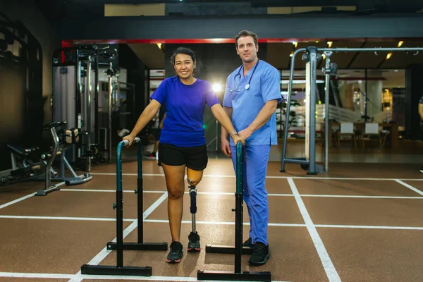 理学療法士は彼女の患者と義肢を世話する 理学療法士は スポーツセンターで義肢装具士の女性を支援します 理学療法士と患者と一緒にリハビリとジム — ストック写真