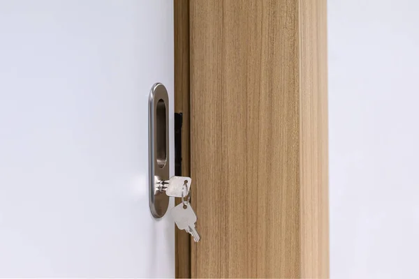 Keys stuck in a lock in door. Key with keychain in the door