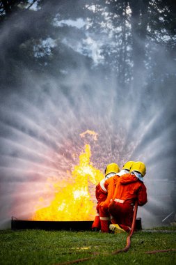 Firefighter Concept. Fireman using water and extinguisher to fighting with fire flame. firefighters fighting a fire with a hose and water during a firefighting training exercise