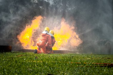 Firefighter Concept. Fireman using water and extinguisher to fighting with fire flame. firefighters fighting a fire with a hose and water during a firefighting training exercise