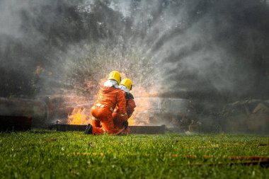 Firefighter Concept. Fireman using water and extinguisher to fighting with fire flame. firefighters fighting a fire with a hose and water during a firefighting training exercise