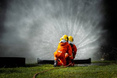 Firefighter Concept. Fireman using water and extinguisher to fighting with fire flame. firefighters fighting a fire with a hose and water during a firefighting training exercise