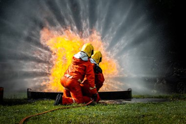 Firefighter Concept. Fireman using water and extinguisher to fighting with fire flame. firefighters fighting a fire with a hose and water during a firefighting training exercise