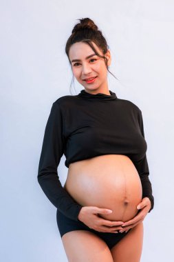 Hamile karnı. Ayakta duran ve çıplak karnına dokunan bir kadın. Güzel, hamile bir karın. Hamile bir kadının karnı. Hamile kadın dinleniyor..