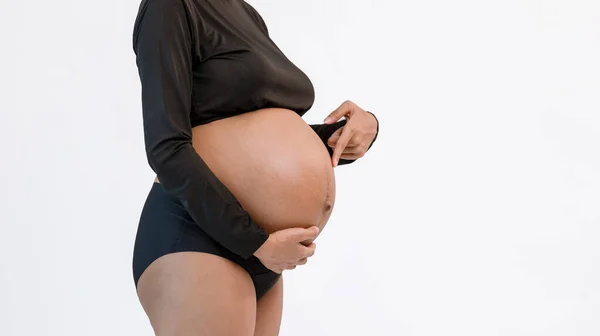 Pregnant belly. Woman standing and touching her naked big belly. a cute pregnant belly. belly of a pregnant woman. pregnant woman stand rest.