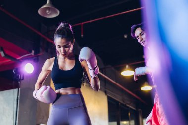 Boks kulübünde kadın boksör eğitimi. Kadın boks dövüşçüleri spor salonunda antrenman yapıyor. Güçlü kaslı kadın spor salonunda pembe boks eldivenleriyle kutu çalışması yapıyor..