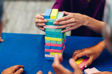 Ahşap blok kulesi, risk ve proje yönetimi stratejisi oynayan kıdemli insanlar. Domino bloklarıyla iş riski kavramı. Evde Jenga blok kaldırma oyunu oynayan yaşlı insanlar