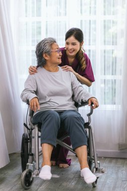 Bakıcı hemşire parkta yürüyen kıdemli bir hastayla ilgilenir. Hemşire yaşlı kadına yardım ediyor.