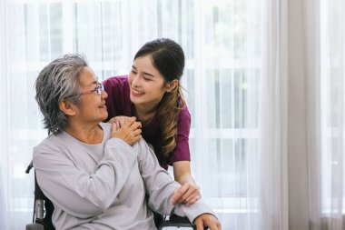 Bakıcı hemşire parkta yürüyen kıdemli bir hastayla ilgilenir. Hemşire yaşlı kadına yardım ediyor.