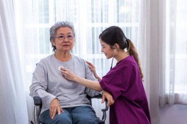 Bakıcı hemşire parkta yürüyen kıdemli bir hastayla ilgilenir. Hemşire yaşlı kadına yardım ediyor.