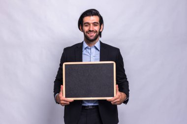 Beyaz arka planda tebeşir tahtası tutan bir iş adamı. Kara tahtayı tutan yakışıklı bir iş adamı. Küçük çerçeveli tahtayı tutan yakışıklı bir adam.