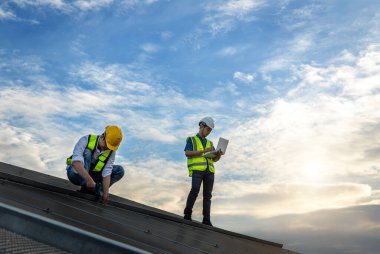 Çatıda çalışan mühendis güneş paneli kuruyor. Mühendis ya da işçi iş binasının çatısındaki güneş panelleri ya da güneş pilleri üzerinde çalışır.
