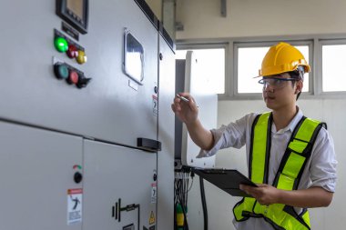 Kontrol odasında çalışan elektrik mühendisi. Elektrik mühendisi kontrol odasındaki güç dağıtım dolabını kontrol ediyor.