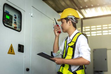 Electrical engineer working in control room. Electrical engineer man checking Power Distribution Cabinet in the control room clipart