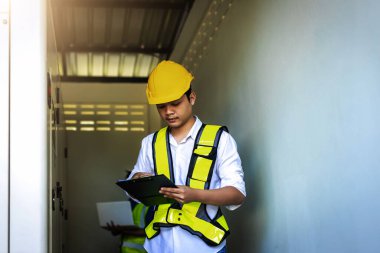 Kontrol odasında çalışan elektrik mühendisi. Elektrik mühendisi kontrol odasındaki güç dağıtım dolabını kontrol ediyor.