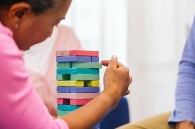 Ahşap blok kulesi, risk ve proje yönetimi stratejisi oynayan kıdemli insanlar. Domino bloklarıyla iş riski kavramı. Evde Jenga blok kaldırma oyunu oynayan yaşlı insanlar