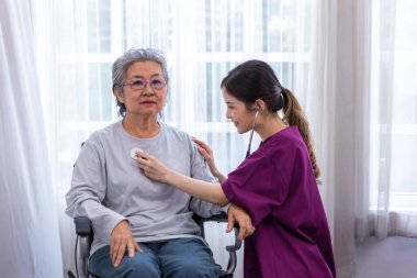 Bakıcı hemşire parkta yürüyen kıdemli bir hastayla ilgilenir. Hemşire yaşlı kadına yardım ediyor.