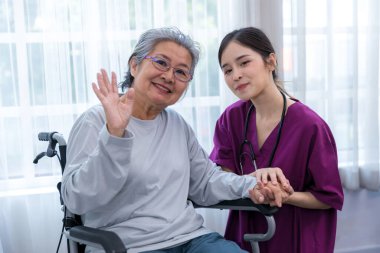 Bakıcı hemşire parkta yürüyen kıdemli bir hastayla ilgilenir. Hemşire yaşlı kadına yardım ediyor.