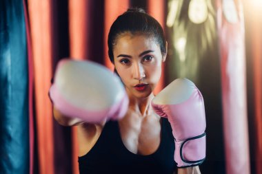 Boks kulübünde kadın boksör eğitimi. Kadın boks dövüşçüleri spor salonunda antrenman yapıyor. Güçlü kaslı kadın spor salonunda pembe boks eldivenleriyle kutu çalışması yapıyor..