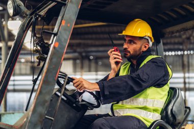 Forklift sürücüsünde çalışan adam fabrika lojistik gemisinde çalışmaktan mutlu. Depoda forklift şoförü var. Forklift sürücüsü depoda araçta oturuyor.