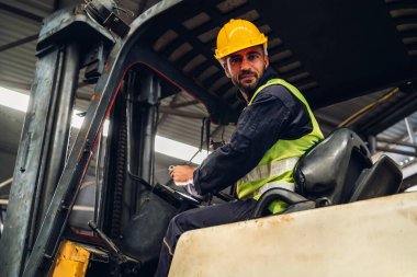 Forklift sürücüsünde çalışan adam fabrika lojistik gemisinde çalışmaktan mutlu. Depoda forklift şoförü var. Forklift sürücüsü depoda araçta oturuyor.
